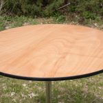 A round table featuring a wooden top supported by sleek metal legs, showcasing a modern and elegant design.