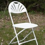 A white folding chair positioned in the grass, offering a simple yet inviting spot for relaxation outdoors.